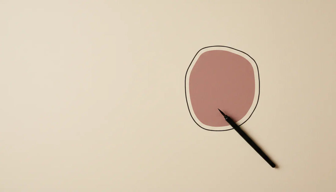 Calm minimalist still life on a warm cream background: a single bold rounded black — why do i get overstimulated so easily