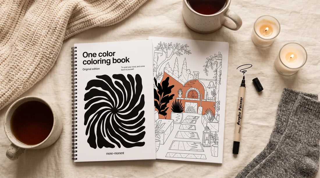 A cozy gift flat-lay for her: knit blanket, tea, wool socks and an open one-color coloring book with a single pen