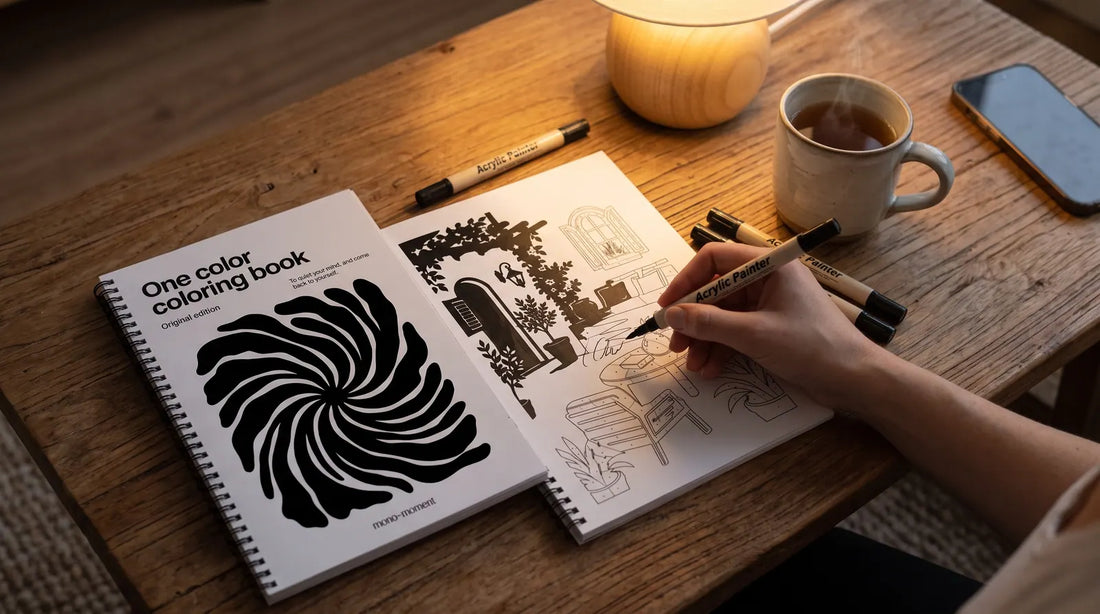 A phone lying face down next to an open coloring book with one bold shape being filled with a single pen
