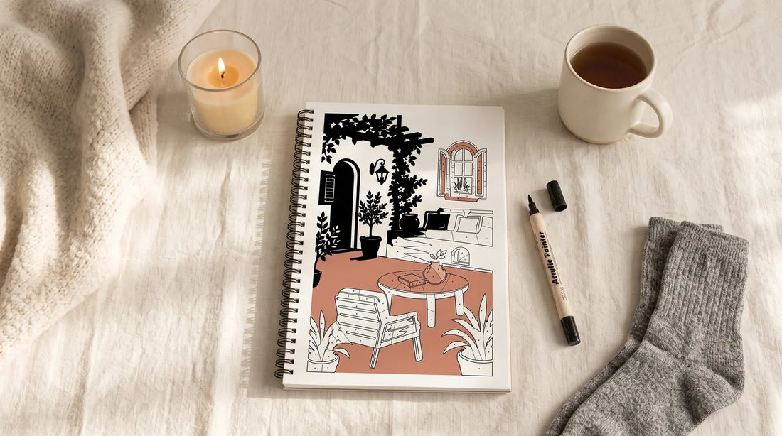 A hygge flat-lay: knit blanket, candle, tea and an open one-color coloring book with a single pen