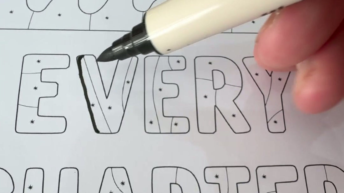 Close-up of a hand coloring bold letters in the One Color Coloring Book