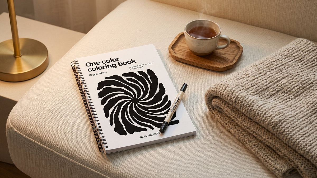 The One Color Coloring Book on a sofa cushion with a brush pen and a cup of tea