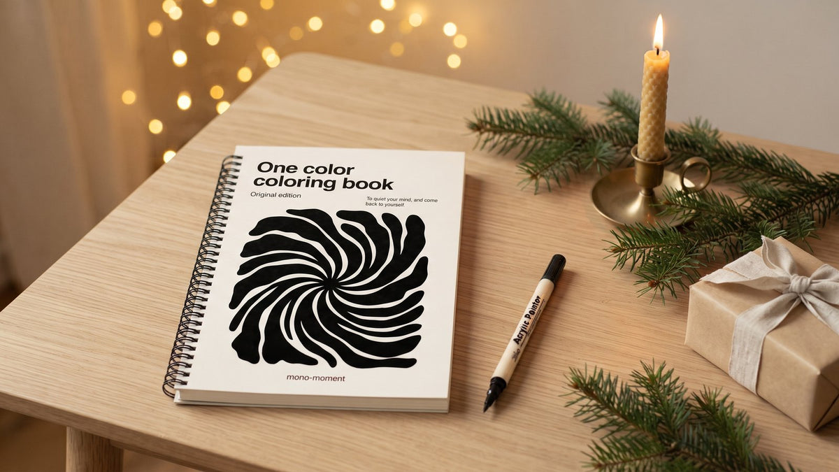 The One Color Coloring Book on a wooden table with fir branches, a candle and a brush pen