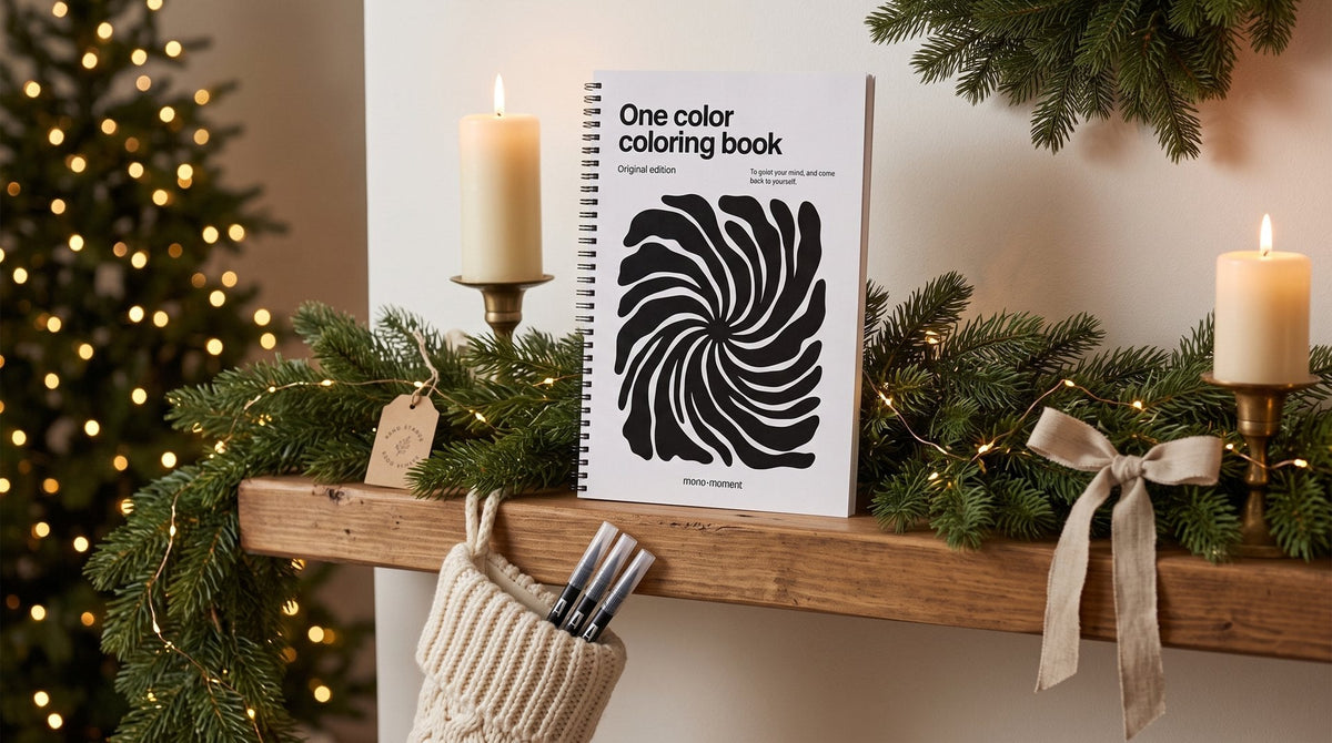 Three brush pens in a knitted Christmas stocking on a mantel, with the One Color Coloring Book propped beside it