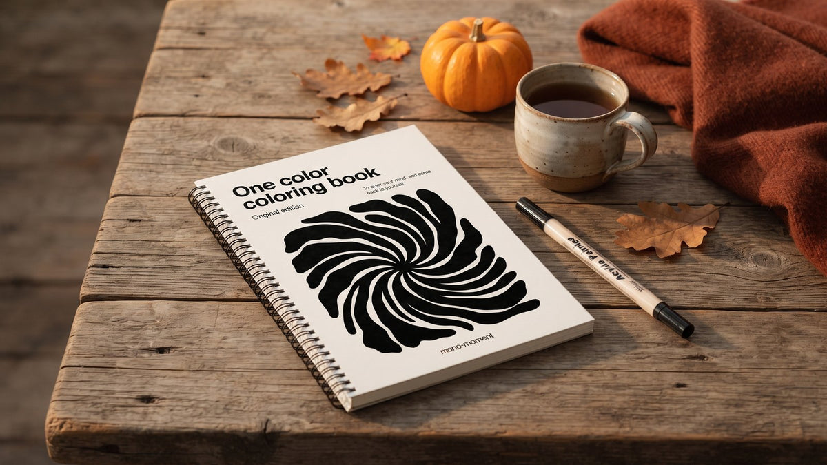 The One Color Coloring Book on a wooden table with autumn leaves, a mug and a brush pen