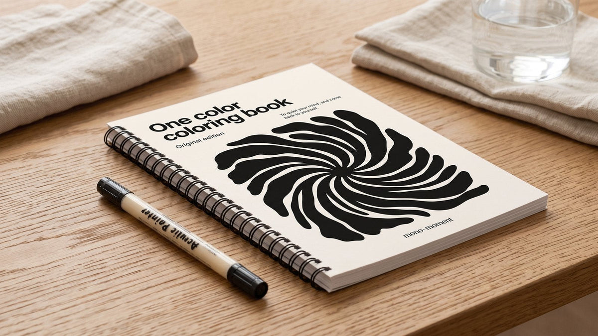 Close view of the black spiral binding of the One Color Coloring Book lying flat on a wooden table
