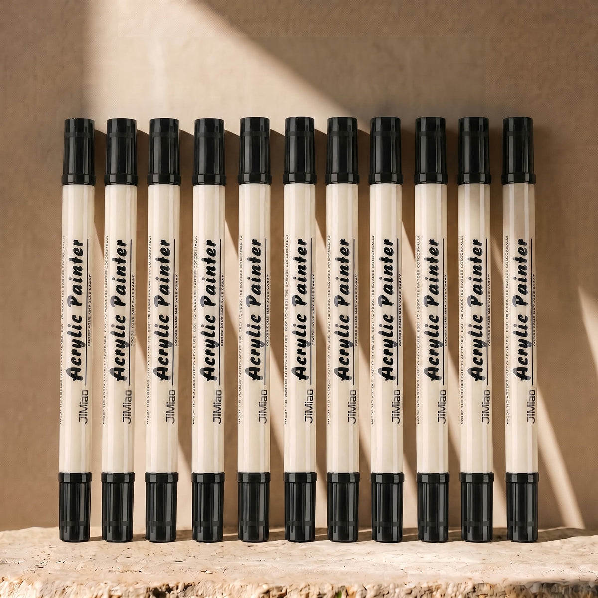 Twelve black-ink dual-tip brush pens arranged on a warm background