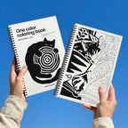 One Color Coloring Book Cats Special Edition held up against a blue sky: the cover and an inside cat page